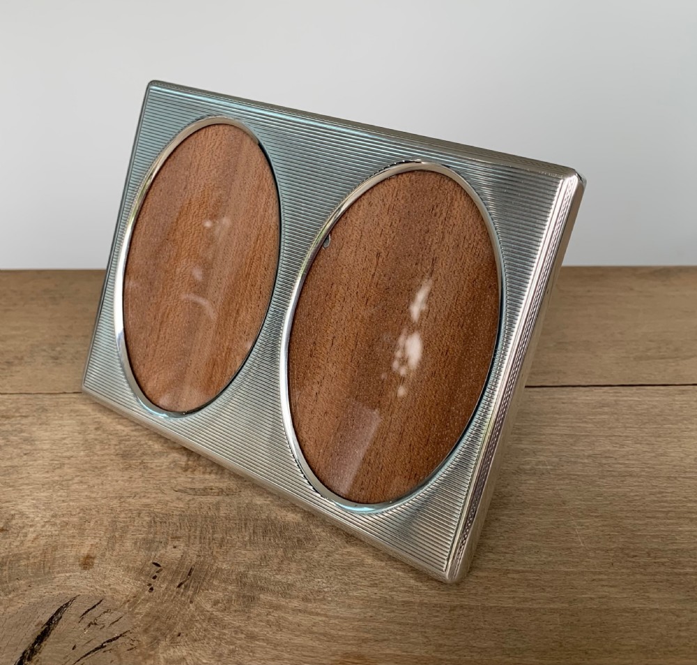 A rectangular sterling silver twin photo frame with linear engine-turned texturing and two oval apertures. View II