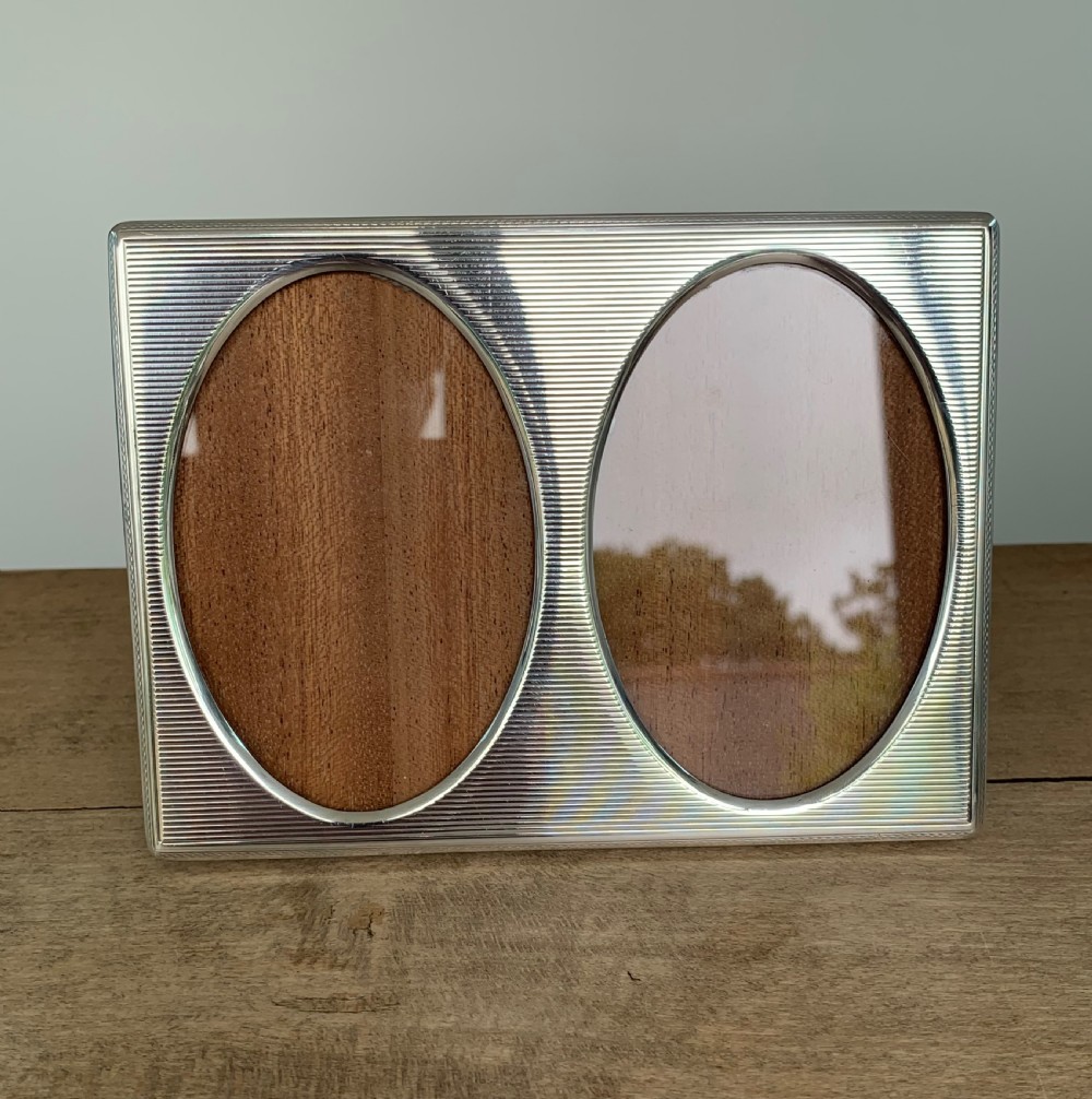 A rectangular sterling silver twin photo frame with linear engine-turned texturing and two oval apertures. View III