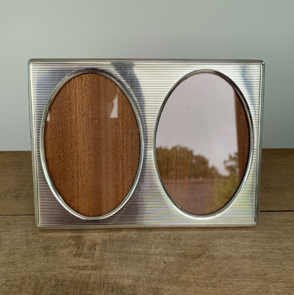 A rectangular sterling silver twin photo frame with linear engine-turned texturing and two oval apertures. View IV