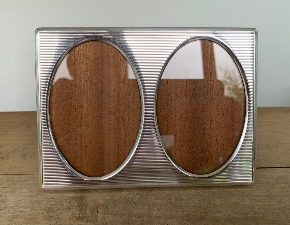 A rectangular sterling silver twin photo frame with linear engine-turned texturing and two oval apertures. View V