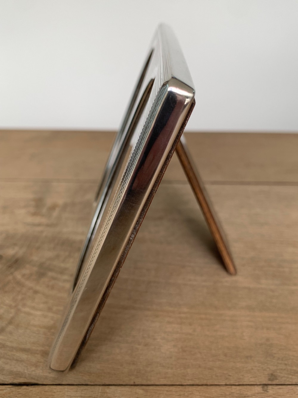 A rectangular sterling silver twin photo frame with linear engine-turned texturing and two oval apertures. View VII