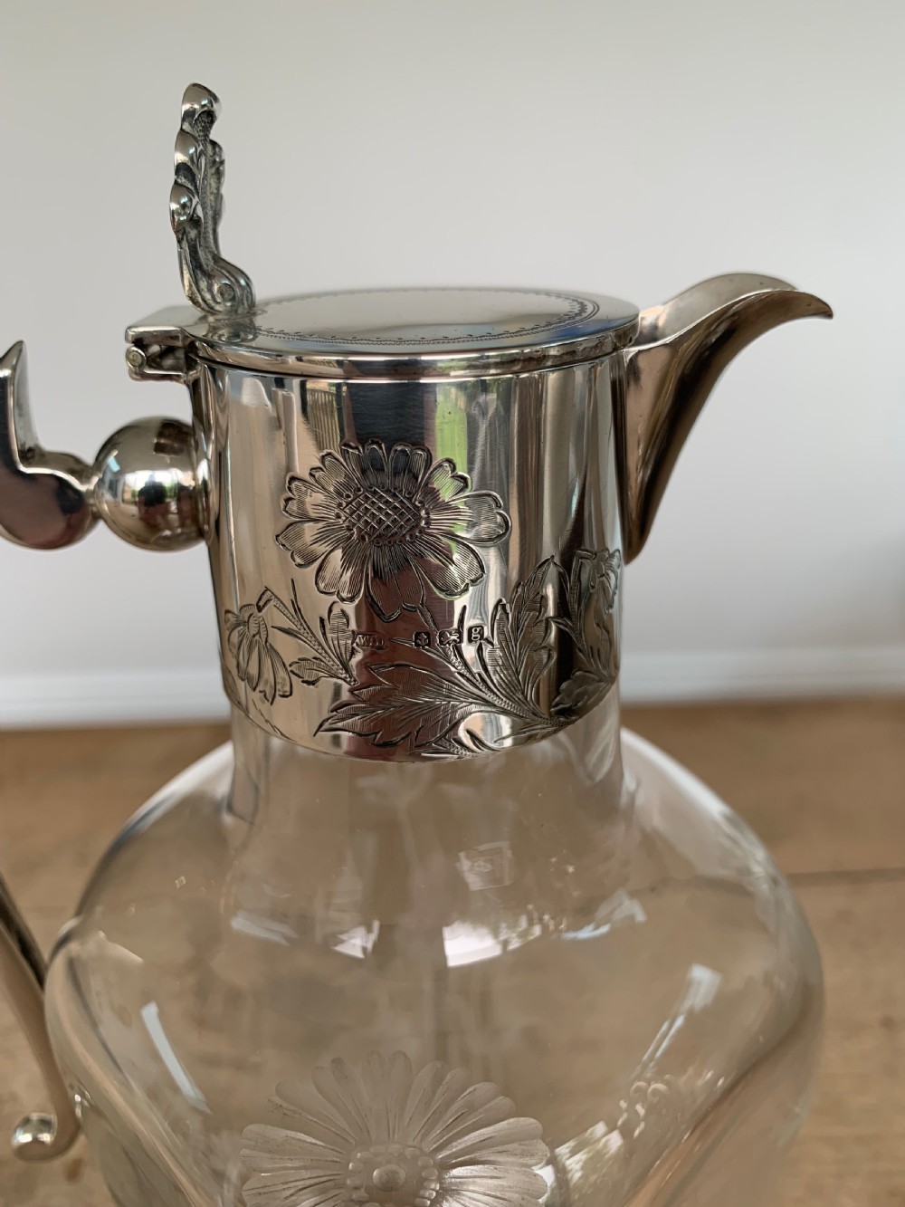 An Edwardian clear glass claret jug featuring wheel-engraved daisy motifs and a hallmarked sterling silver collar with handle. View VII