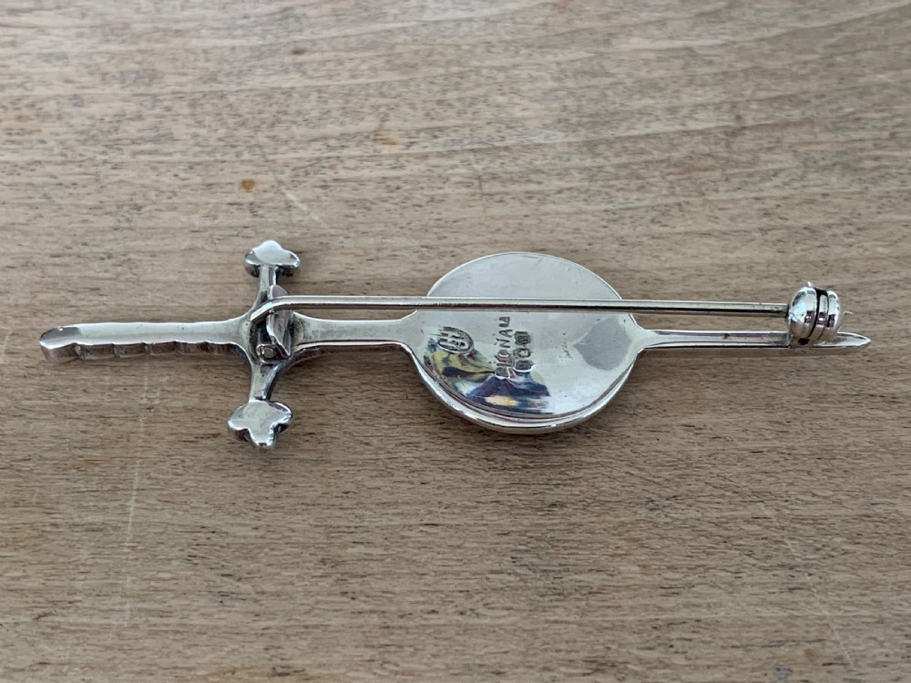 A sterling silver brooch designed in the shape of a sword passing through a circular shield embellished with intricate Celtic knotwork. View III