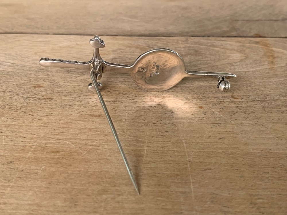 A sterling silver brooch designed in the shape of a sword passing through a circular shield embellished with intricate Celtic knotwork. View VI