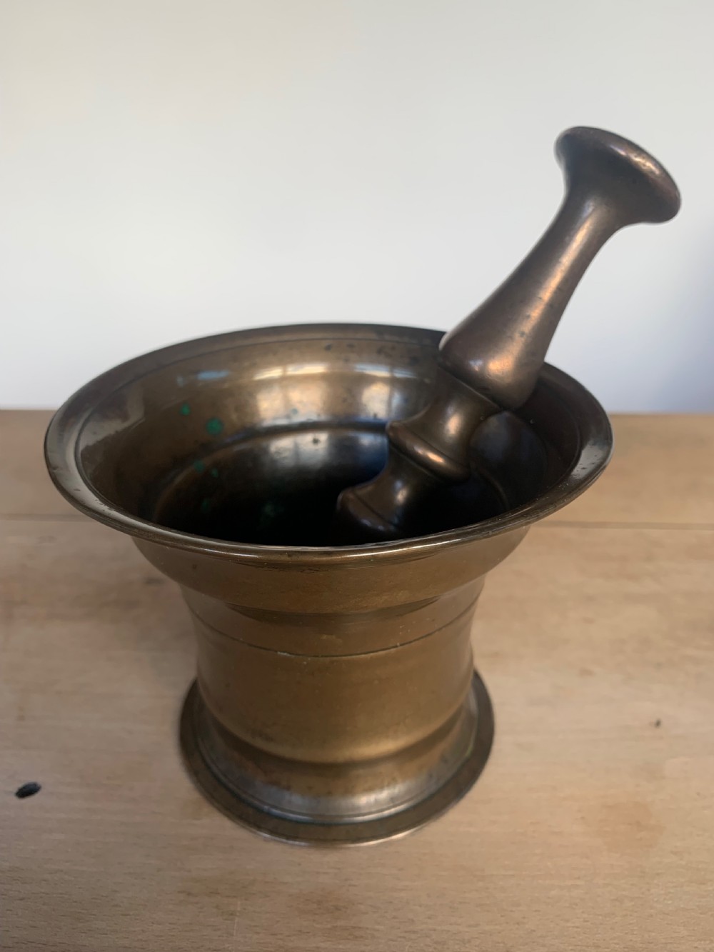 An antique cast bronze mortar with a flared rim and turned waist, accompanied by a matching metal pestle. View III