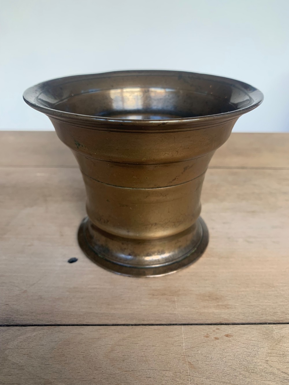 An antique cast bronze mortar with a flared rim and turned waist, accompanied by a matching metal pestle. View IV