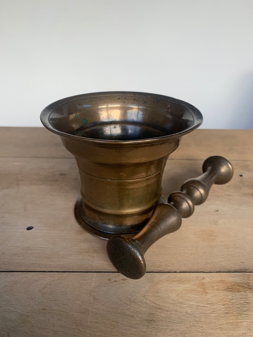 An antique cast bronze mortar with a flared rim and turned waist, accompanied by a matching metal pestle. View VI