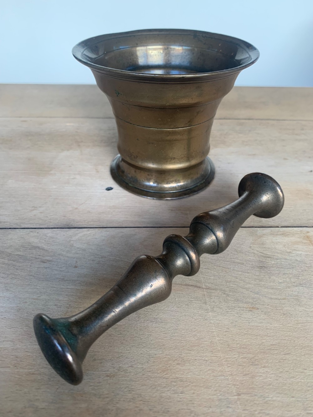 An antique cast bronze mortar with a flared rim and turned waist, accompanied by a matching metal pestle. View VII