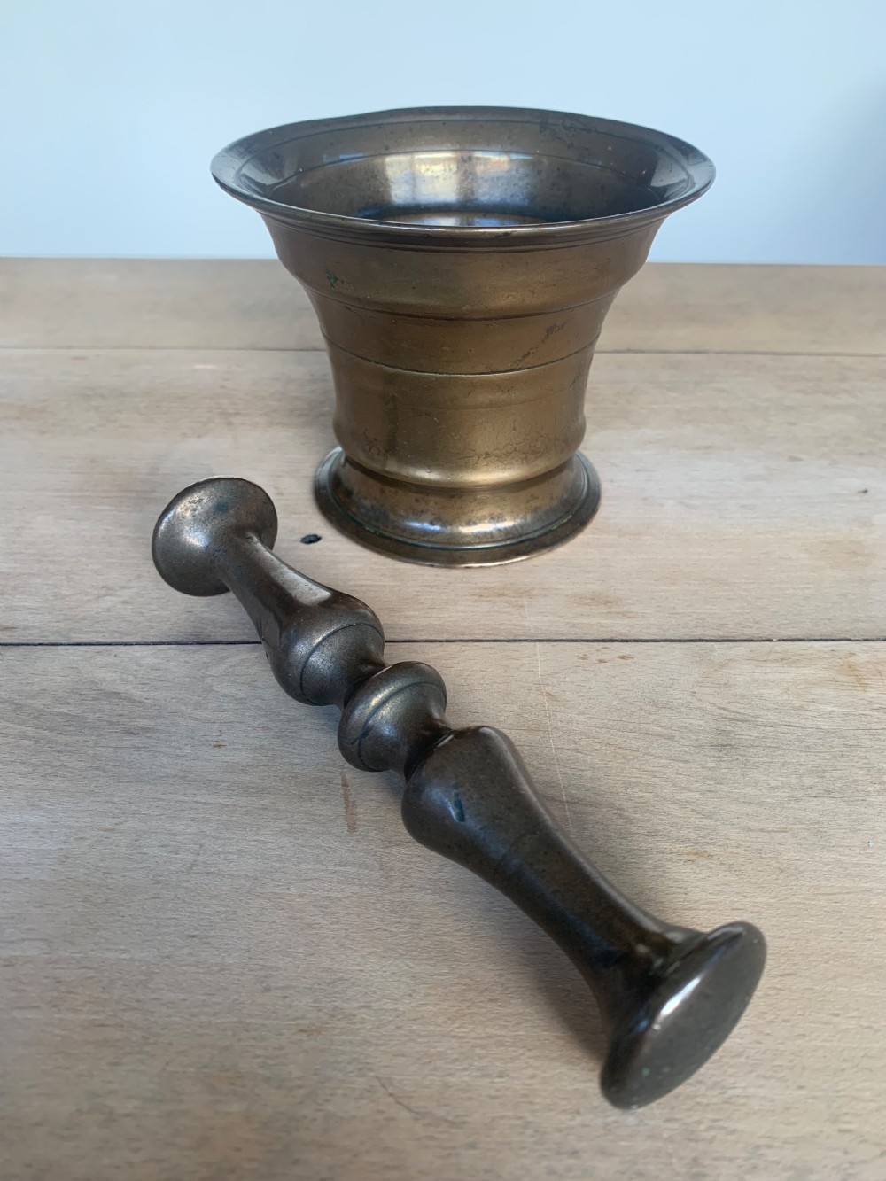 An antique cast bronze mortar with a flared rim and turned waist, accompanied by a matching metal pestle. View VIII