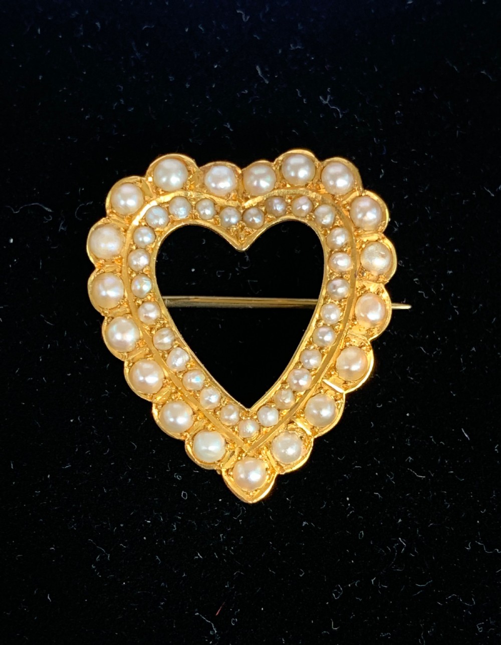 A Victorian 18ct yellow gold heart brooch featuring a double border of set seed pearls around an open centre.
