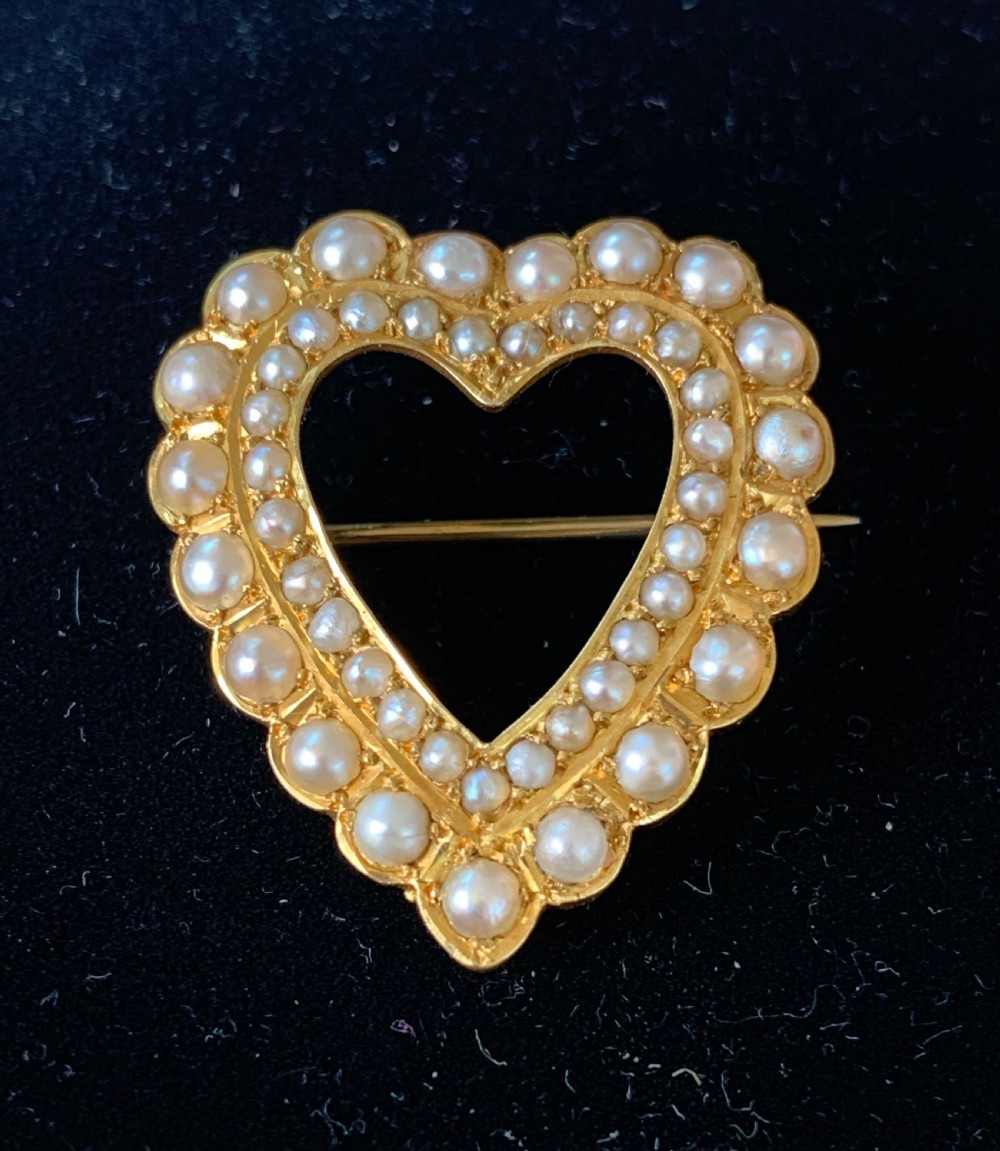 A Victorian 18ct yellow gold heart brooch featuring a double border of set seed pearls around an open centre. View II