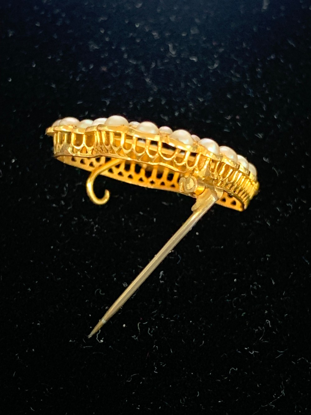 A Victorian 18ct yellow gold heart brooch featuring a double border of set seed pearls around an open centre. View V