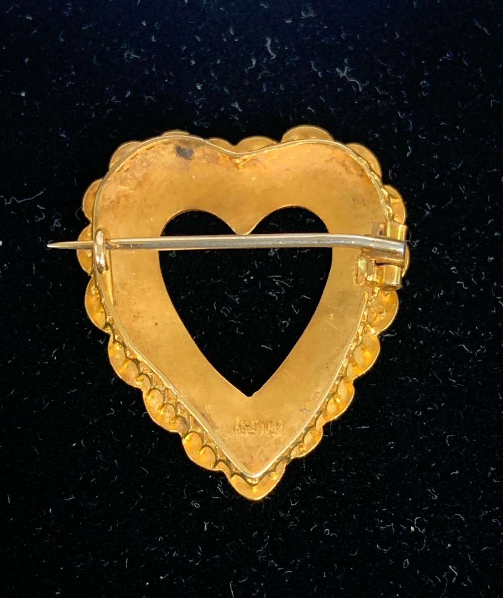 A Victorian 18ct yellow gold heart brooch featuring a double border of set seed pearls around an open centre. View VII