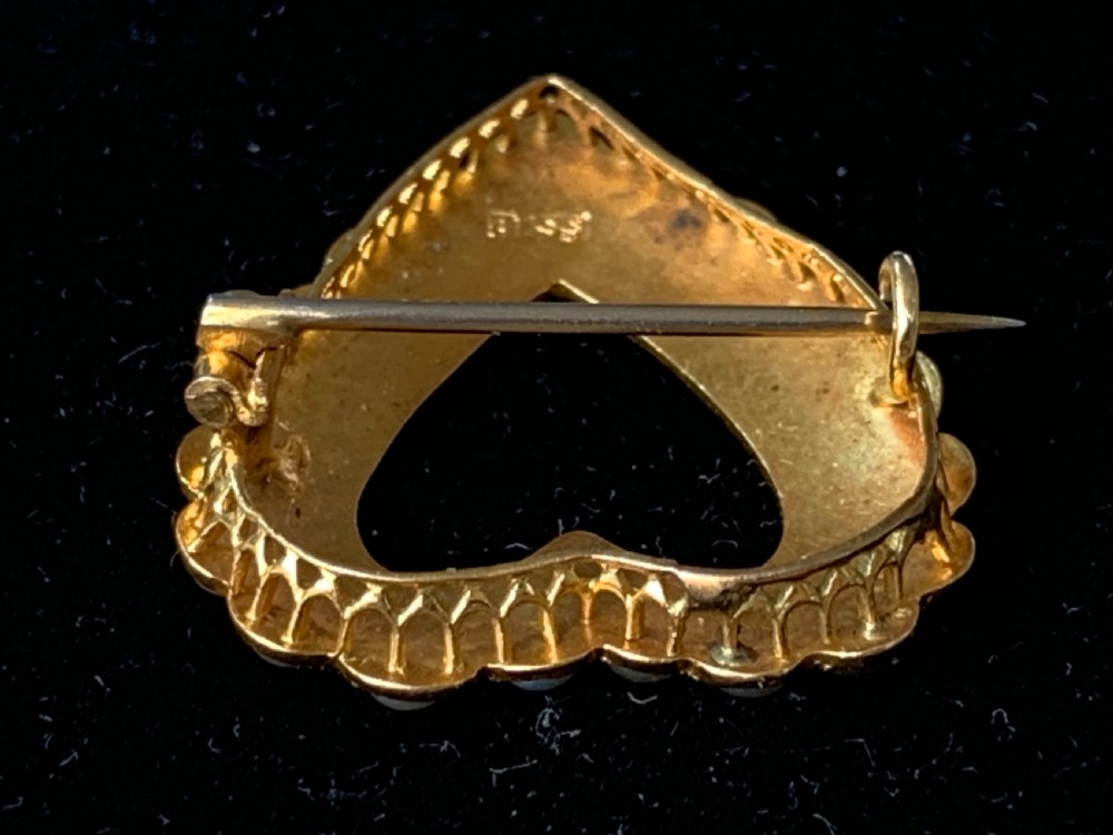 A Victorian 18ct yellow gold heart brooch featuring a double border of set seed pearls around an open centre. View VIII