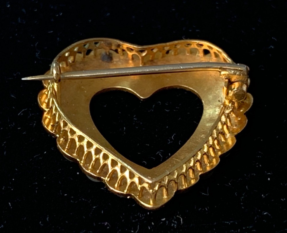 A Victorian 18ct yellow gold heart brooch featuring a double border of set seed pearls around an open centre. View IX