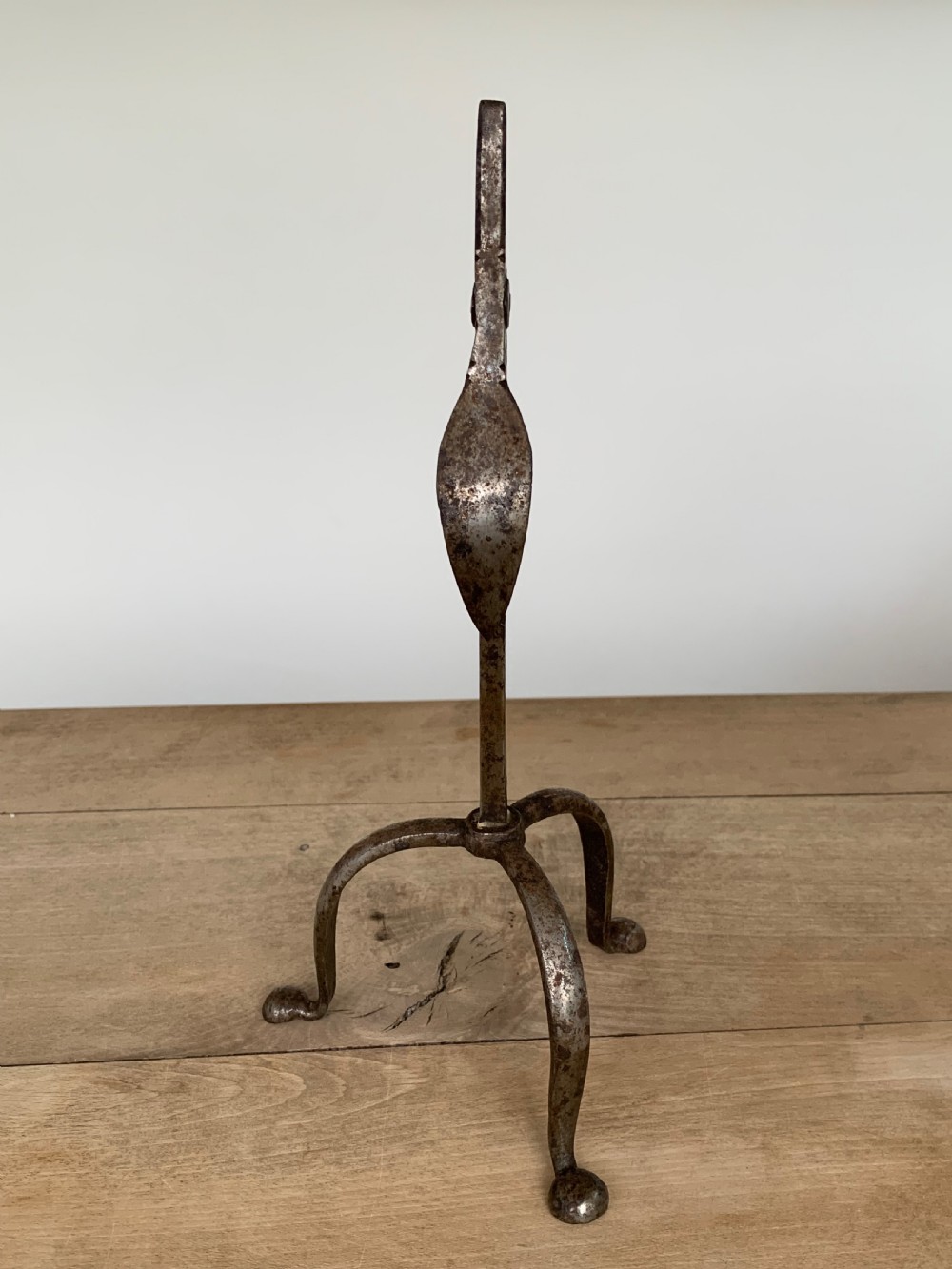 A hand-forged wrought iron rushlight holder featuring a sprung pincer clamp mechanism raised on a curved tripod base. View III