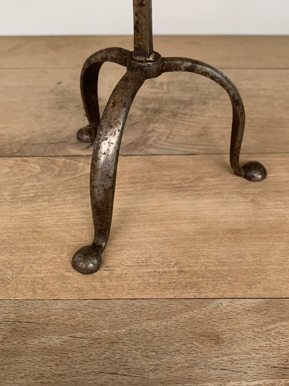 A hand-forged wrought iron rushlight holder featuring a sprung pincer clamp mechanism raised on a curved tripod base. View IV