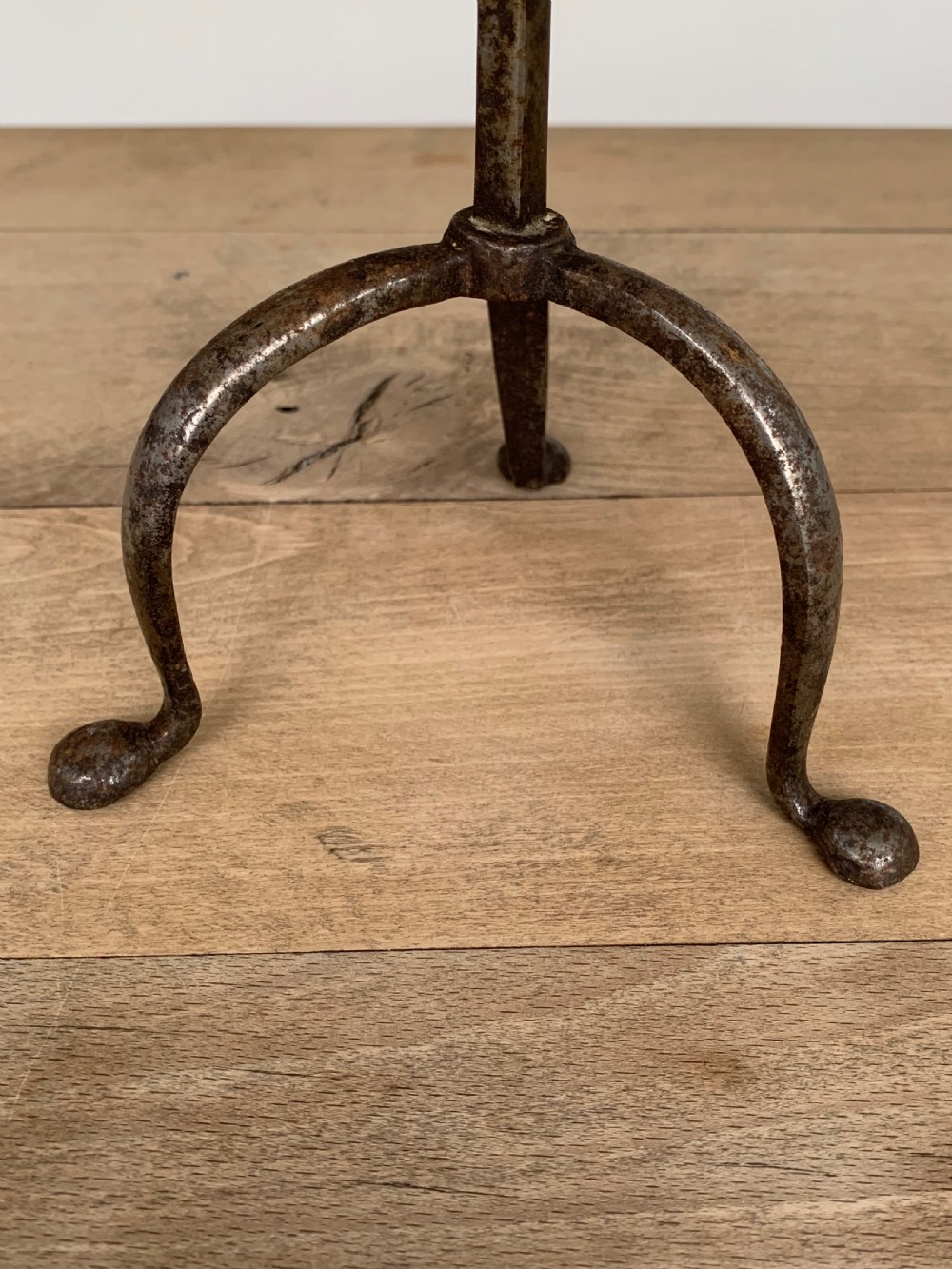 A hand-forged wrought iron rushlight holder featuring a sprung pincer clamp mechanism raised on a curved tripod base. View V