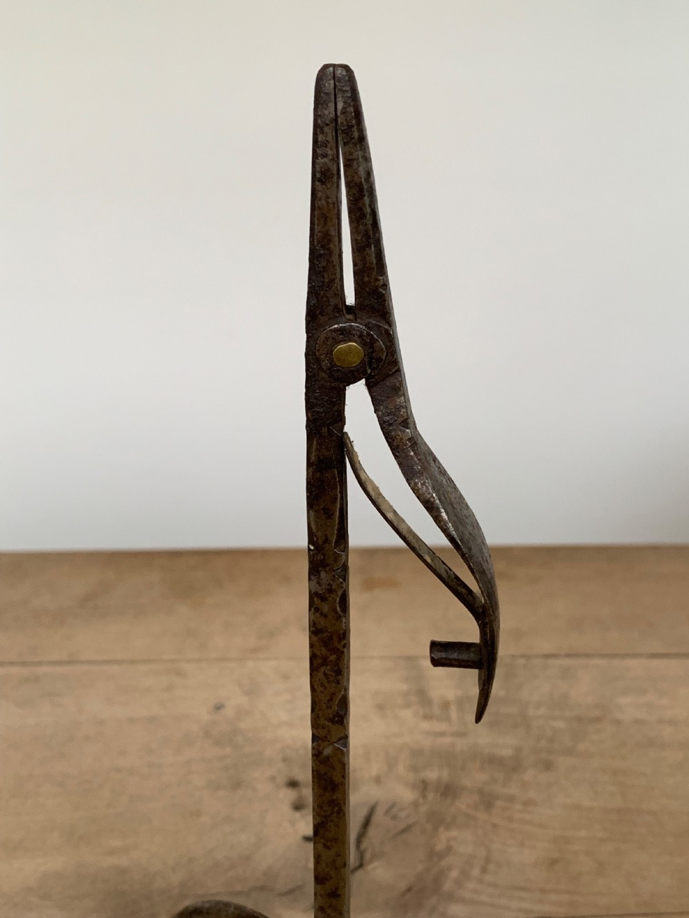 A hand-forged wrought iron rushlight holder featuring a sprung pincer clamp mechanism raised on a curved tripod base. View VI