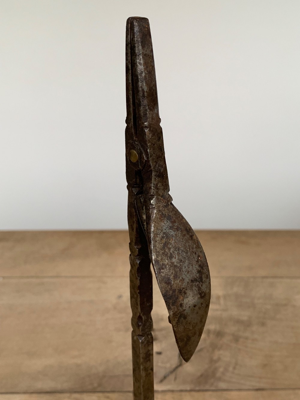 A hand-forged wrought iron rushlight holder featuring a sprung pincer clamp mechanism raised on a curved tripod base. View VII