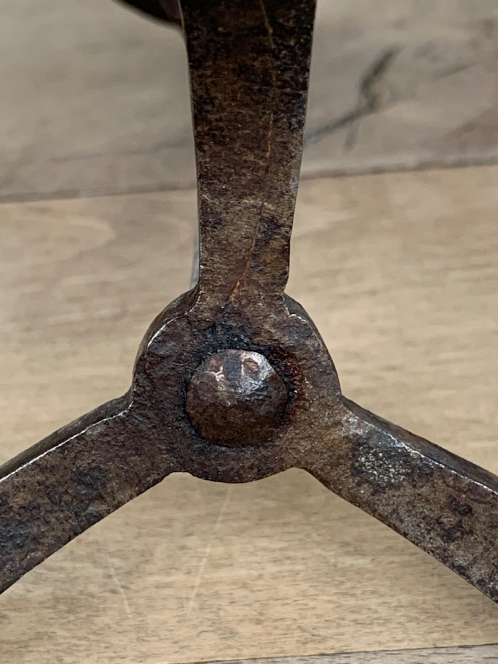 A hand-forged wrought iron rushlight holder featuring a sprung pincer clamp mechanism raised on a curved tripod base. View X