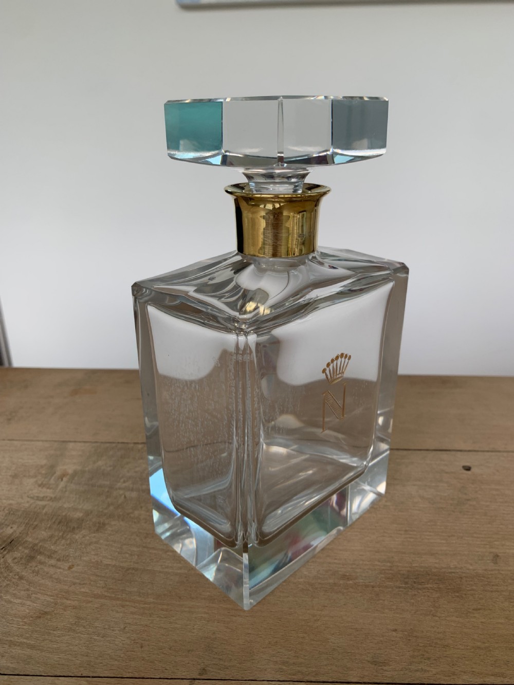 A square clear crystal brandy decanter featuring a silver-gilt collar around the neck, a crowned N monogram on the body, and a rectangular stopper. View VII