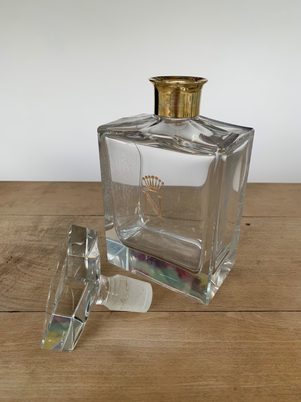 A square clear crystal brandy decanter featuring a silver-gilt collar around the neck, a crowned N monogram on the body, and a rectangular stopper. View VIII