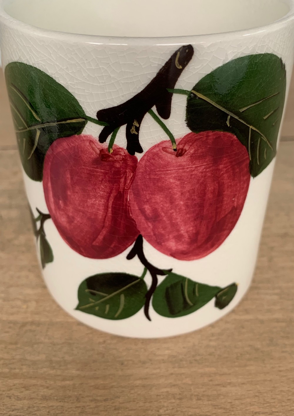 A lidded white ceramic preserve pot decorated with hand-painted red cherries and green leaves, featuring a notch for a spoon. View V