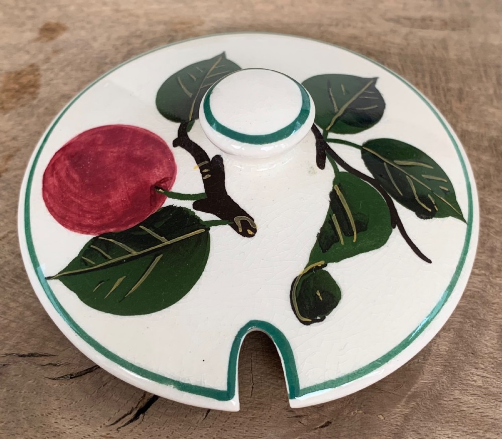A lidded white ceramic preserve pot decorated with hand-painted red cherries and green leaves, featuring a notch for a spoon. View VII