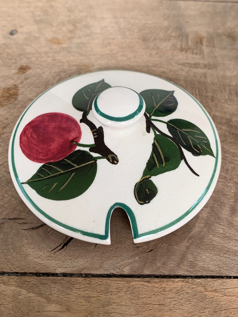 A lidded white ceramic preserve pot decorated with hand-painted red cherries and green leaves, featuring a notch for a spoon. View VIII