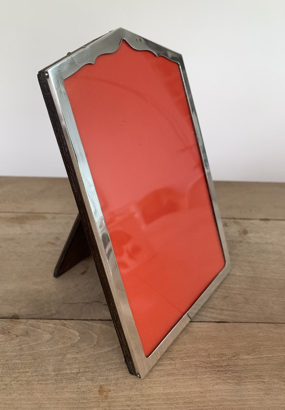An Art Deco sterling silver picture frame featuring an arched top edge and a bright red background insert. View III