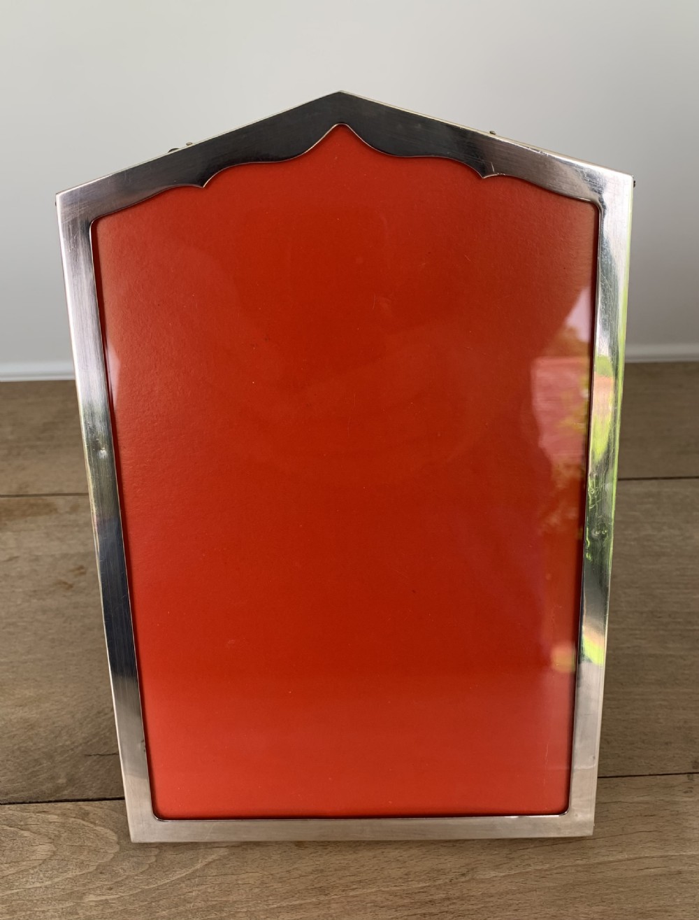 An Art Deco sterling silver picture frame featuring an arched top edge and a bright red background insert. View V