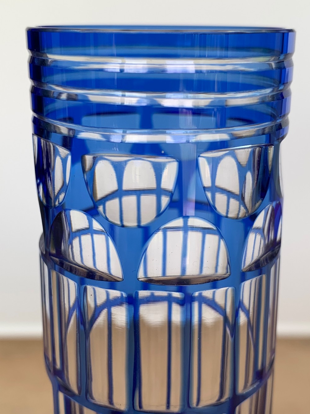 Pair of cobalt blue cut-to-clear crystal champagne flutes featuring geometric architectural patterns and notched square stems on round clear bases. View IX