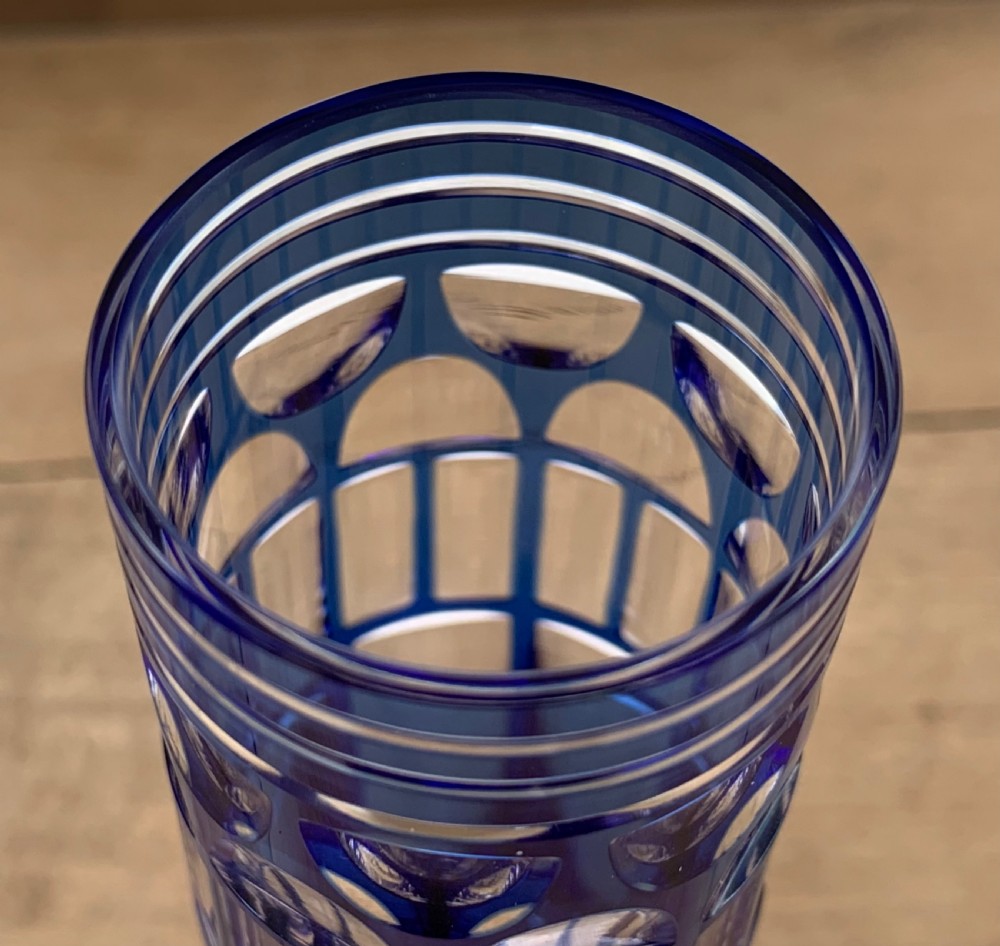 Pair of cobalt blue cut-to-clear crystal champagne flutes featuring geometric architectural patterns and notched square stems on round clear bases. View X