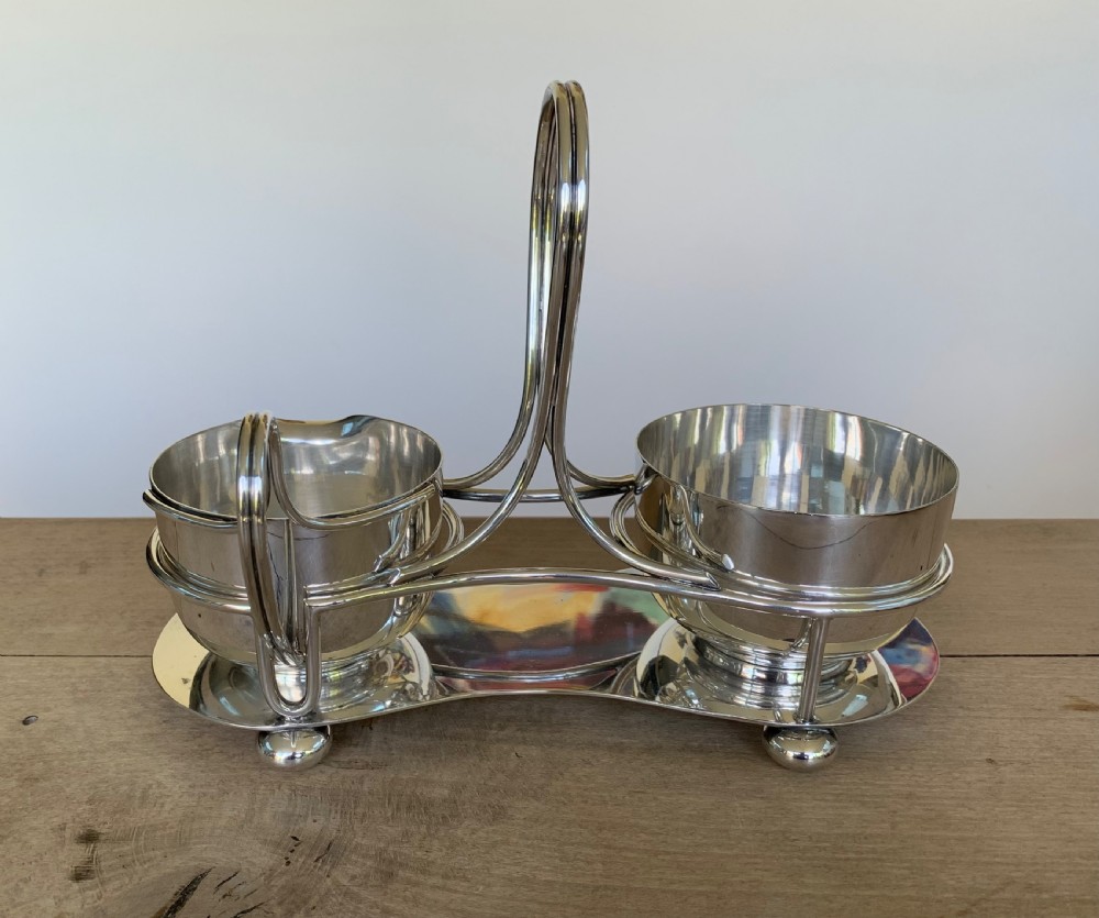 An Art Deco silver-plated sugar bowl and cream jug set within a fitted metal frame featuring a tall loop handle and ball feet. View III