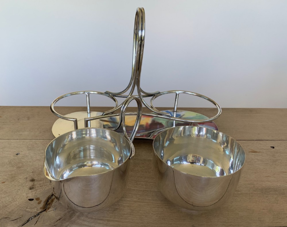 An Art Deco silver-plated sugar bowl and cream jug set within a fitted metal frame featuring a tall loop handle and ball feet. View VIII