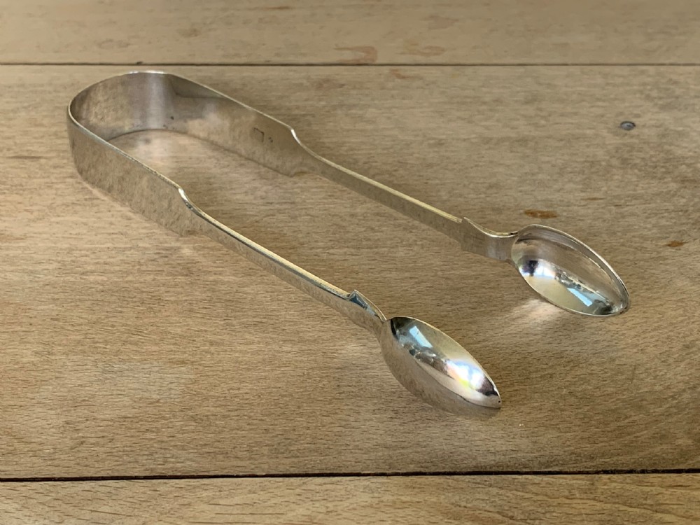 A pair of Victorian sterling silver sugar tongs featuring a plain U-shaped bow and spoon-shaped grips.