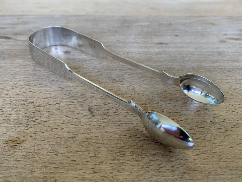 A pair of Victorian sterling silver sugar tongs featuring a plain U-shaped bow and spoon-shaped grips. View II