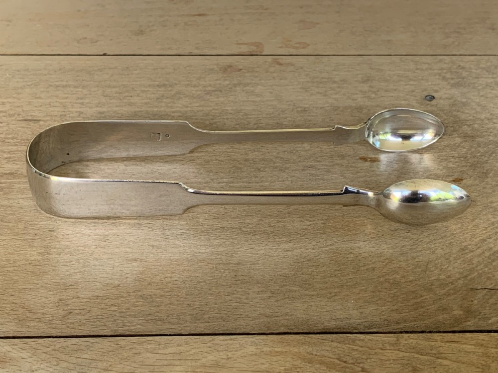 A pair of Victorian sterling silver sugar tongs featuring a plain U-shaped bow and spoon-shaped grips. View IV
