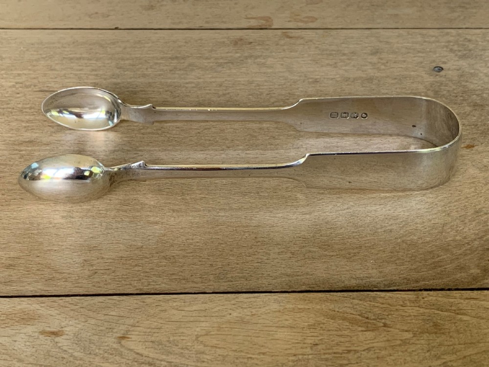A pair of Victorian sterling silver sugar tongs featuring a plain U-shaped bow and spoon-shaped grips. View V