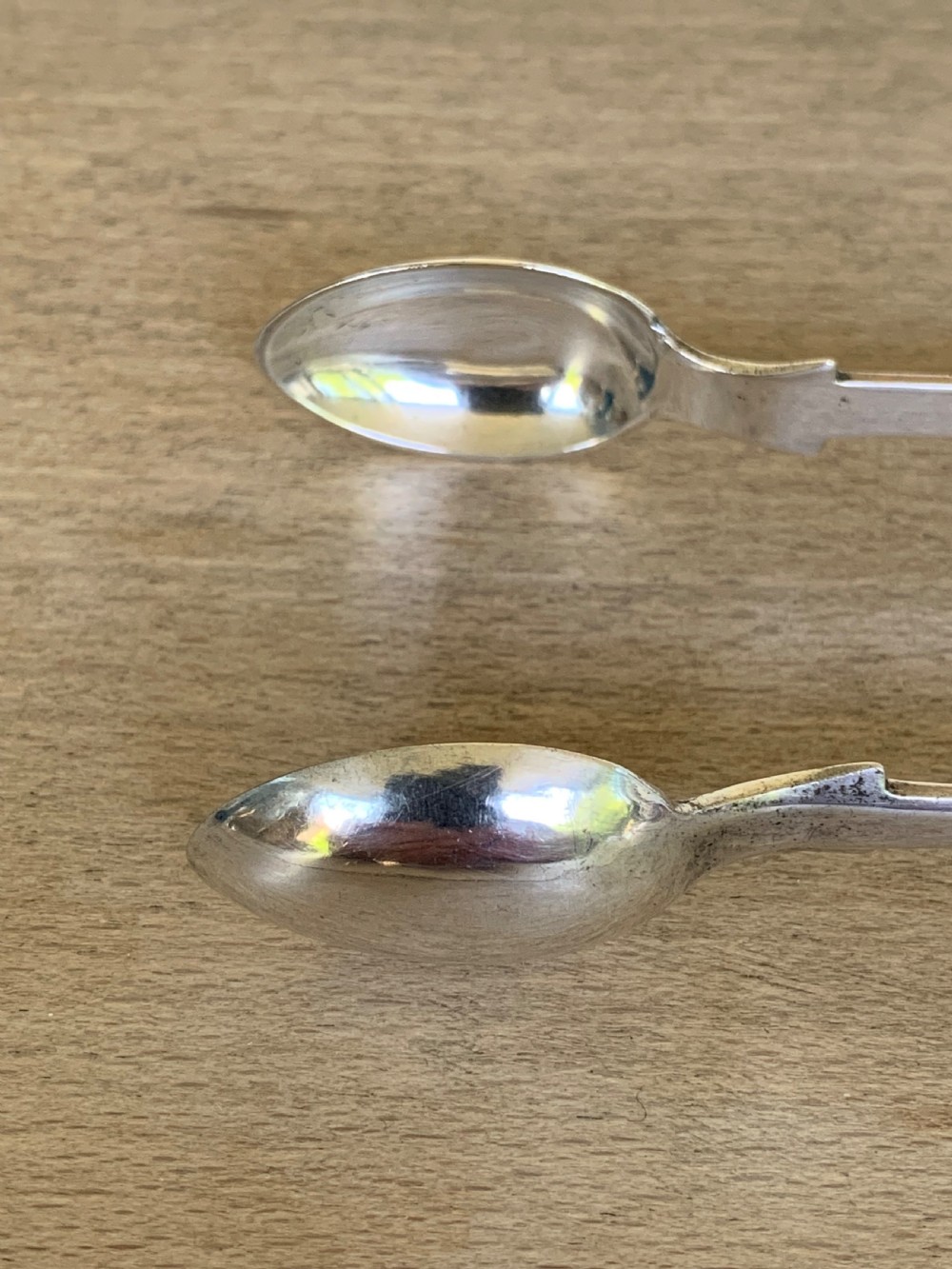 A pair of Victorian sterling silver sugar tongs featuring a plain U-shaped bow and spoon-shaped grips. View VII