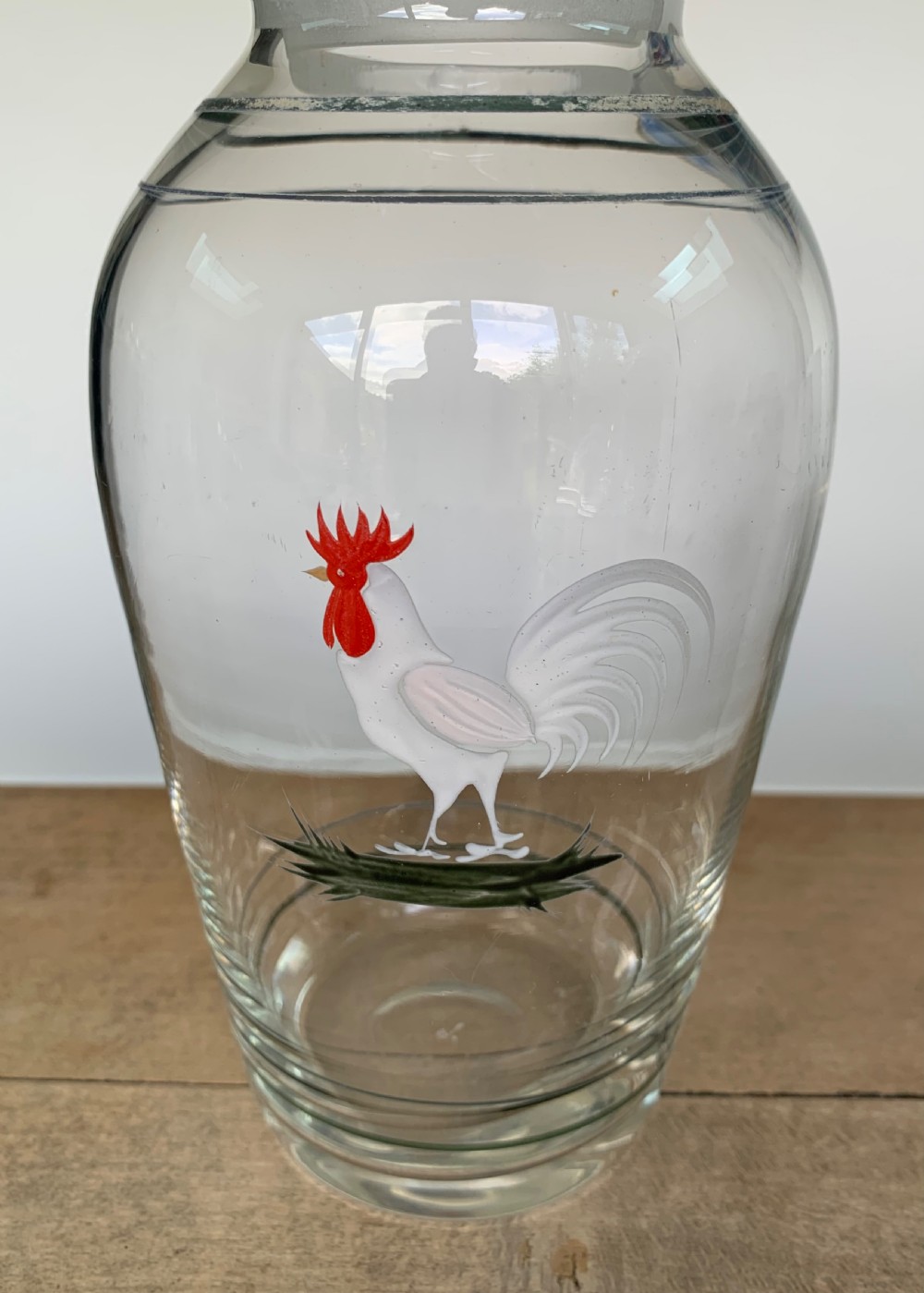 A clear glass Art Deco cocktail shaker featuring a ground glass neck, silver painted lines, and a hand-painted white cockerel motif with a red comb. View II