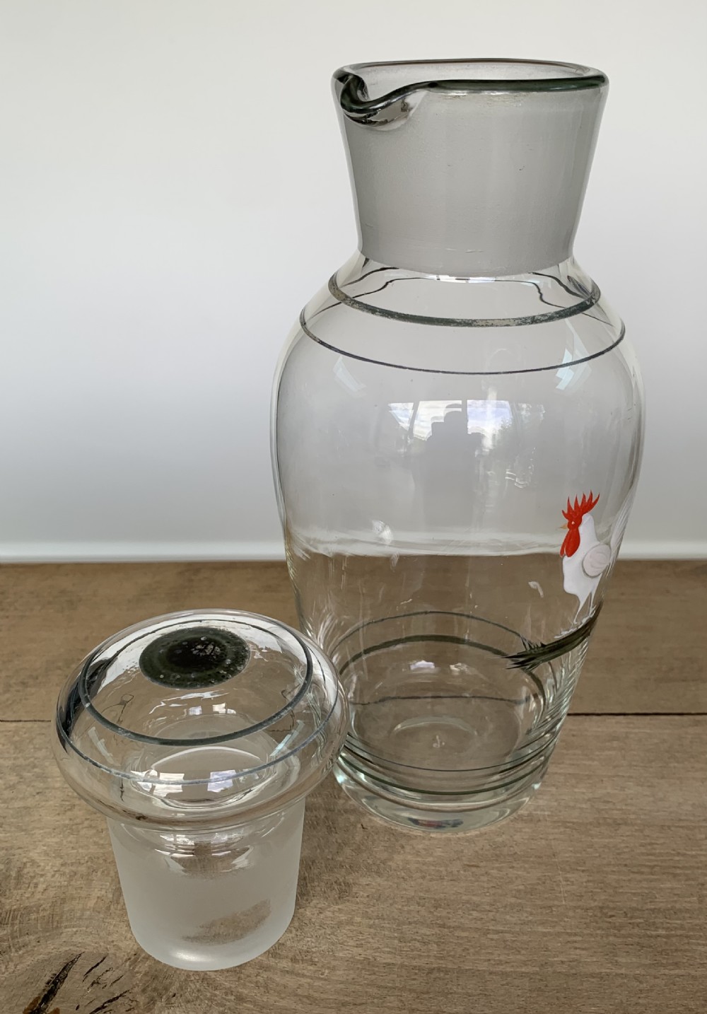 A clear glass Art Deco cocktail shaker featuring a ground glass neck, silver painted lines, and a hand-painted white cockerel motif with a red comb. View VII