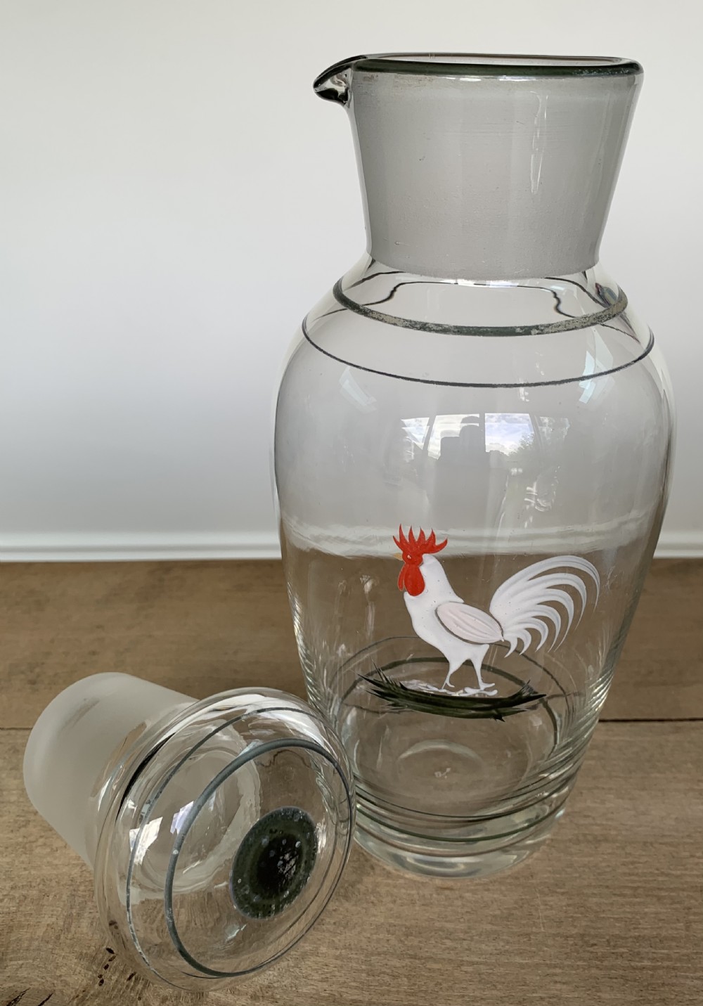A clear glass Art Deco cocktail shaker featuring a ground glass neck, silver painted lines, and a hand-painted white cockerel motif with a red comb. View VIII