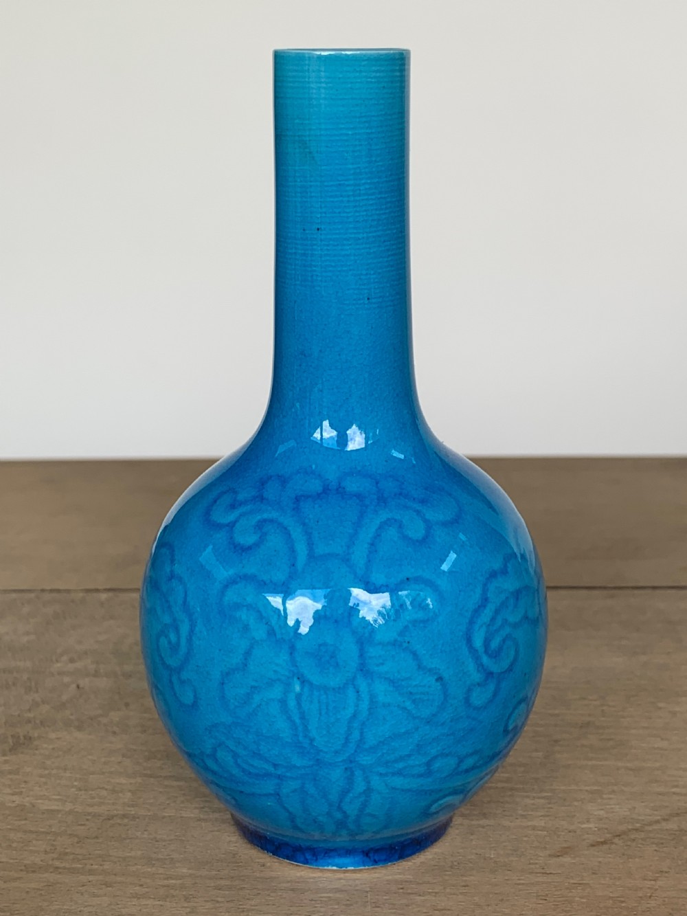 A turquoise blue Chinese porcelain bottle vase featuring a long cylindrical neck, rounded body, and incised peony motifs beneath a glossy glaze. View III