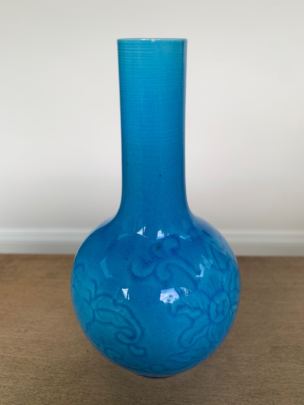A turquoise blue Chinese porcelain bottle vase featuring a long cylindrical neck, rounded body, and incised peony motifs beneath a glossy glaze. View IV
