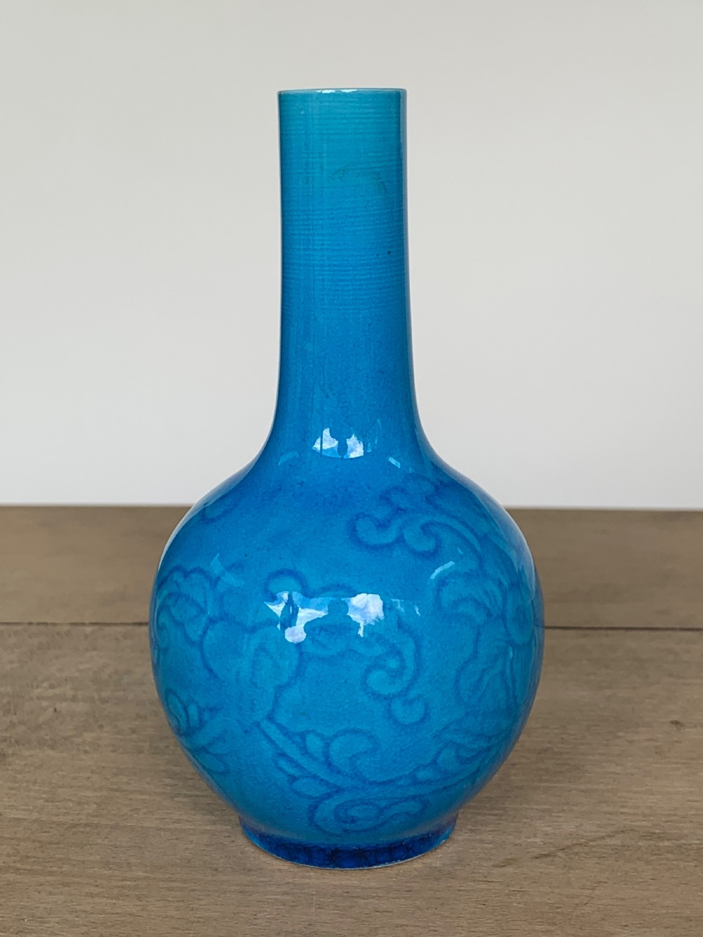 A turquoise blue Chinese porcelain bottle vase featuring a long cylindrical neck, rounded body, and incised peony motifs beneath a glossy glaze. View VI