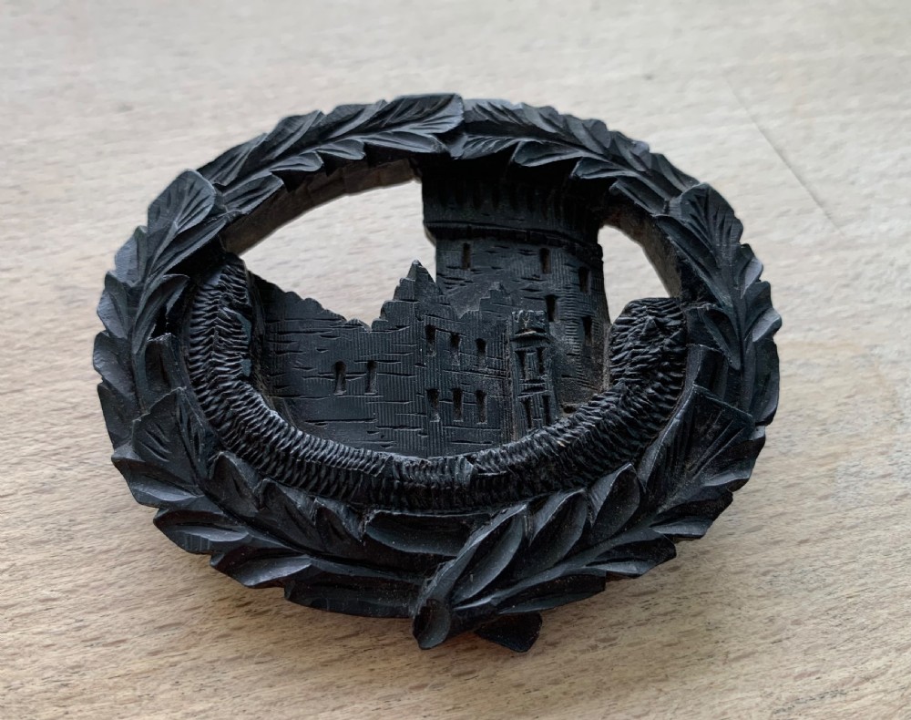 A hand-carved black bog oak oval brooch depicting Blarney Castle enclosed within a leaf border. View II