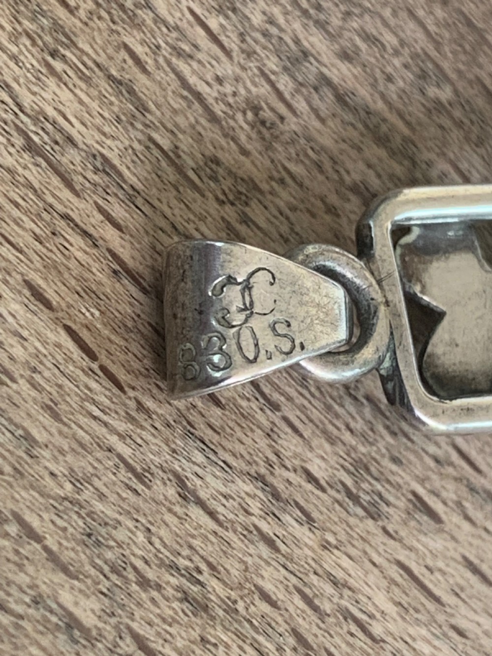 An antique silver cross pendant featuring openwork scrollwork and four-petal floral motifs at the terminals. View VI