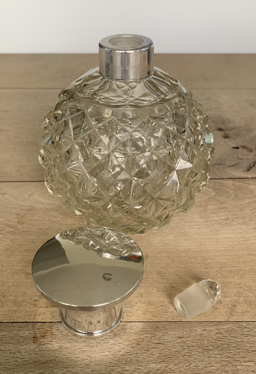 A spherical clear cut glass scent bottle featuring diamond patterns and a polished sterling silver neck collar and lid. View IV